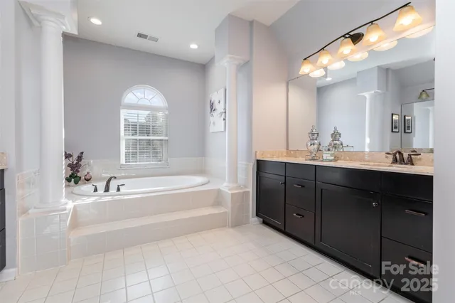 a spacious bathroom with a tub sink double vanity granite and mirror