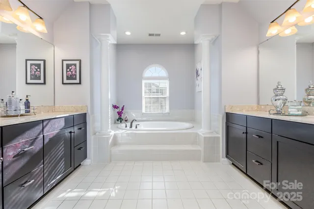 a spacious bathroom with a tub sink double vanity and mirror