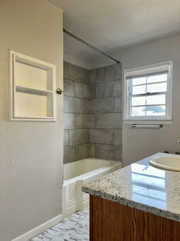 a bathroom with a granite countertop sink a toilet and shower