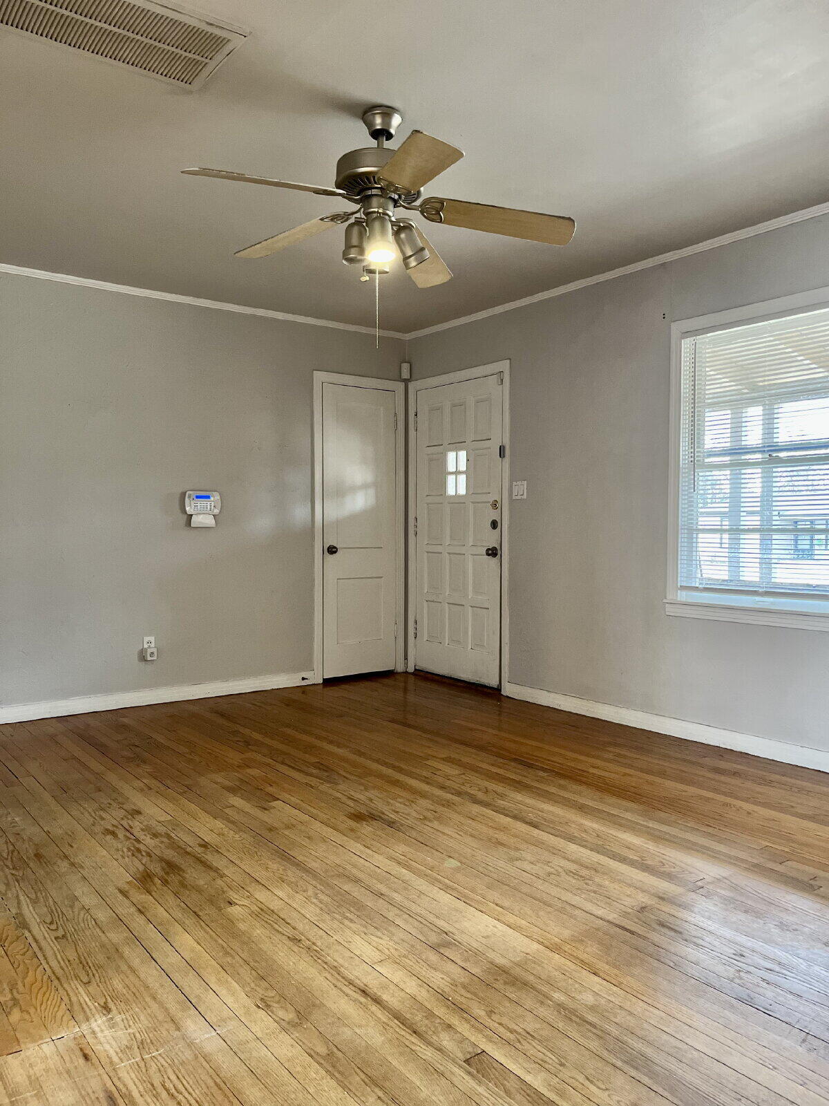 3414 24th Street, Unit FRONT Lubbock, TX 79410 - Photo 3 of 21 an empty room with wooden floor fan and windows