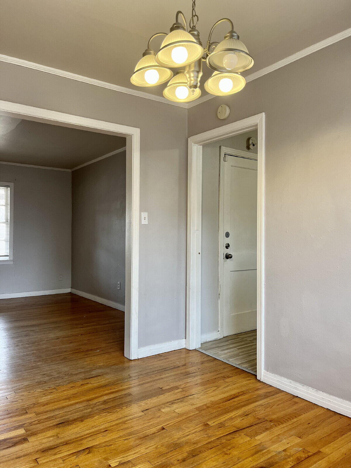 3414 24th Street, Unit FRONT Lubbock, TX 79410 - Photo 6 of 21 a view of an empty room with wooden floor and chandelier