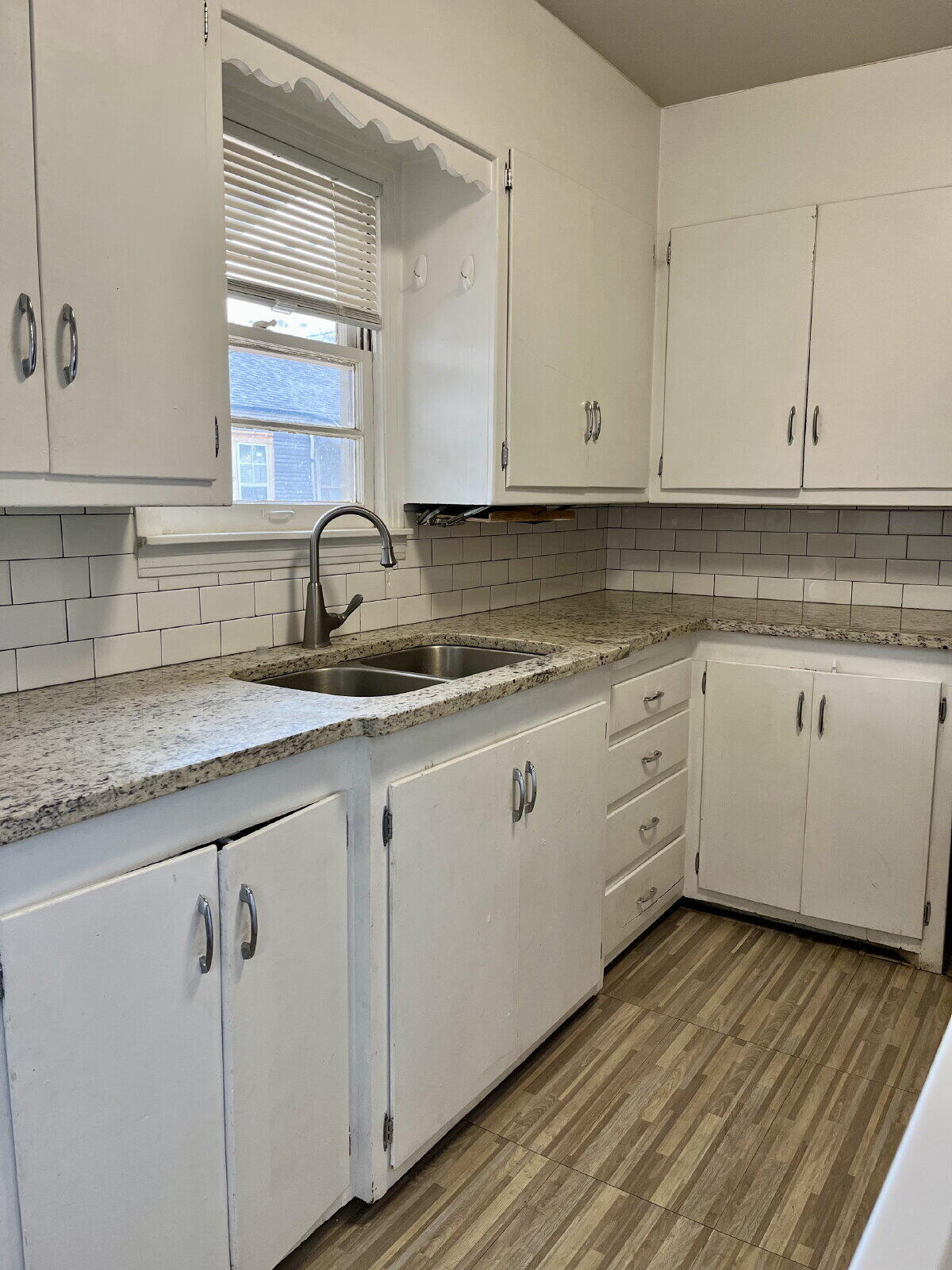 3414 24th Street, Unit FRONT Lubbock, TX 79410 - Photo 9 of 21 a kitchen with granite countertop white cabinets white appliances and a sink