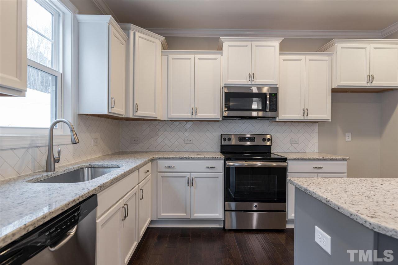 57 Ravencliff Ridge Garner, NC 27529 - Photo 13 of 25 a kitchen with granite countertop a stove a sink and a microwave