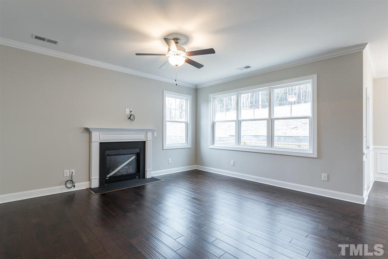 57 Ravencliff Ridge Garner, NC 27529 - Photo 5 of 25 an empty room with wooden floor fireplace and windows