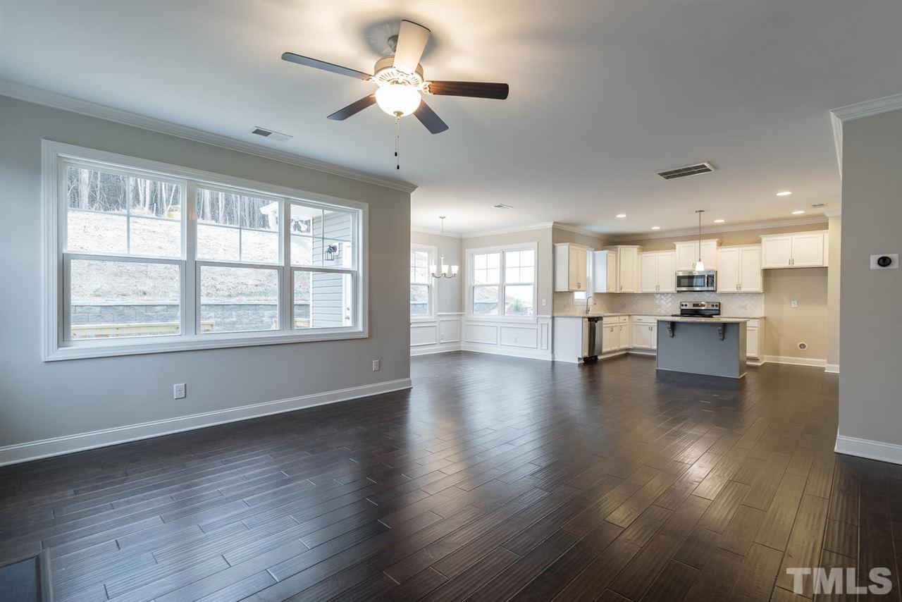 57 Ravencliff Ridge Garner, NC 27529 - Photo 7 of 25 a view of an empty room with wooden floor and a kitchen