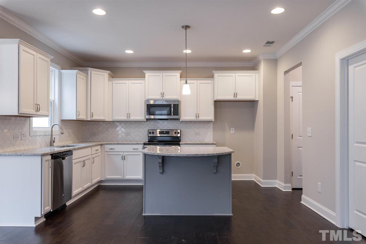 57 Ravencliff Ridge Garner, NC 27529 - Photo 8 of 25 a kitchen with stainless steel appliances granite countertop a sink a stove a refrigerator and white cabinets