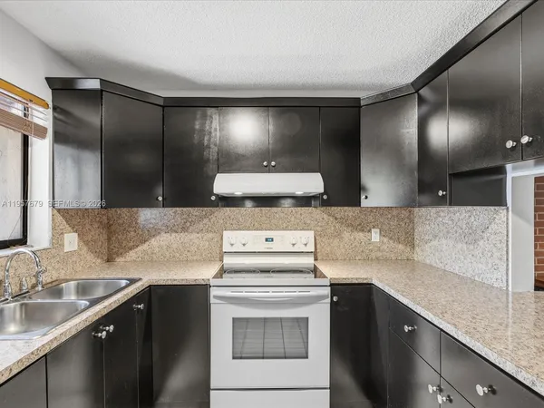 a kitchen with granite countertop a sink stove and cabinets