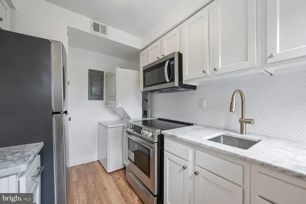a kitchen with stainless steel appliances granite countertop white cabinets a sink a stove a refrigerator and white cabinets