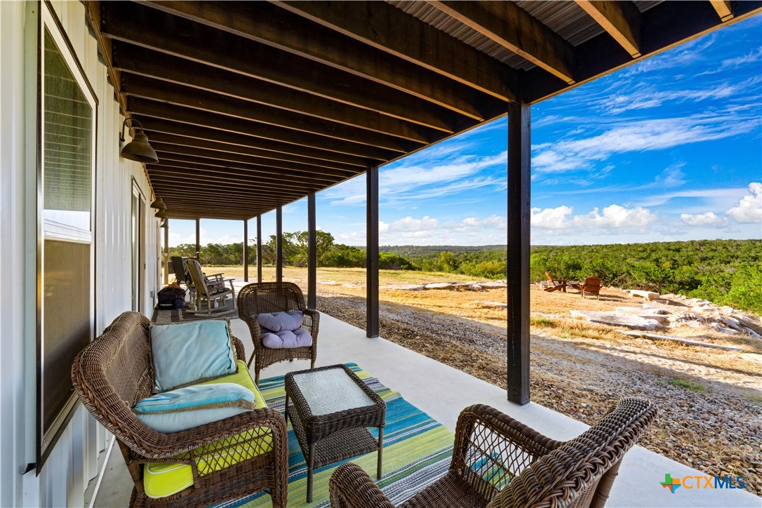 582 Delaware Creek Road Boerne, TX 78006 - Photo 14 of 48 a living room with patio furniture and a floor to ceiling window next to a yard