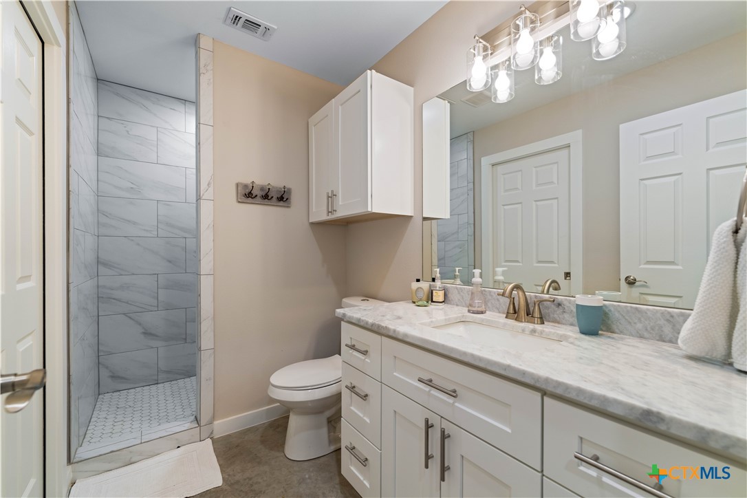 582 Delaware Creek Road Boerne, TX 78006 - Photo 29 of 48 a bathroom with a granite countertop sink a toilet and a mirror