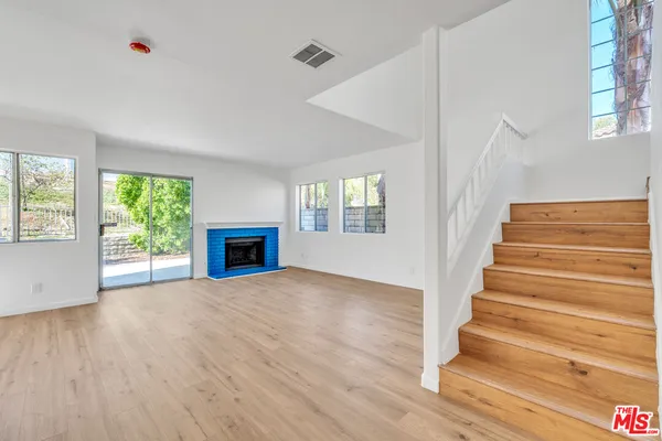 a view of an empty room with wooden floor fireplace and a window