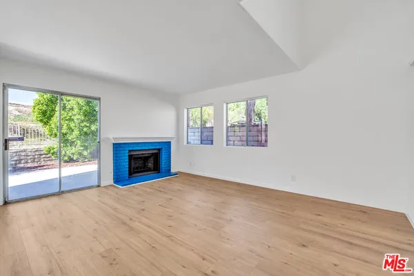 an empty room with windows and fireplace