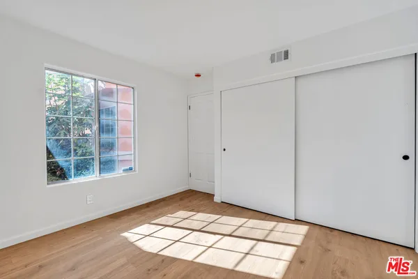 a view of an empty room with wooden floor and windows
