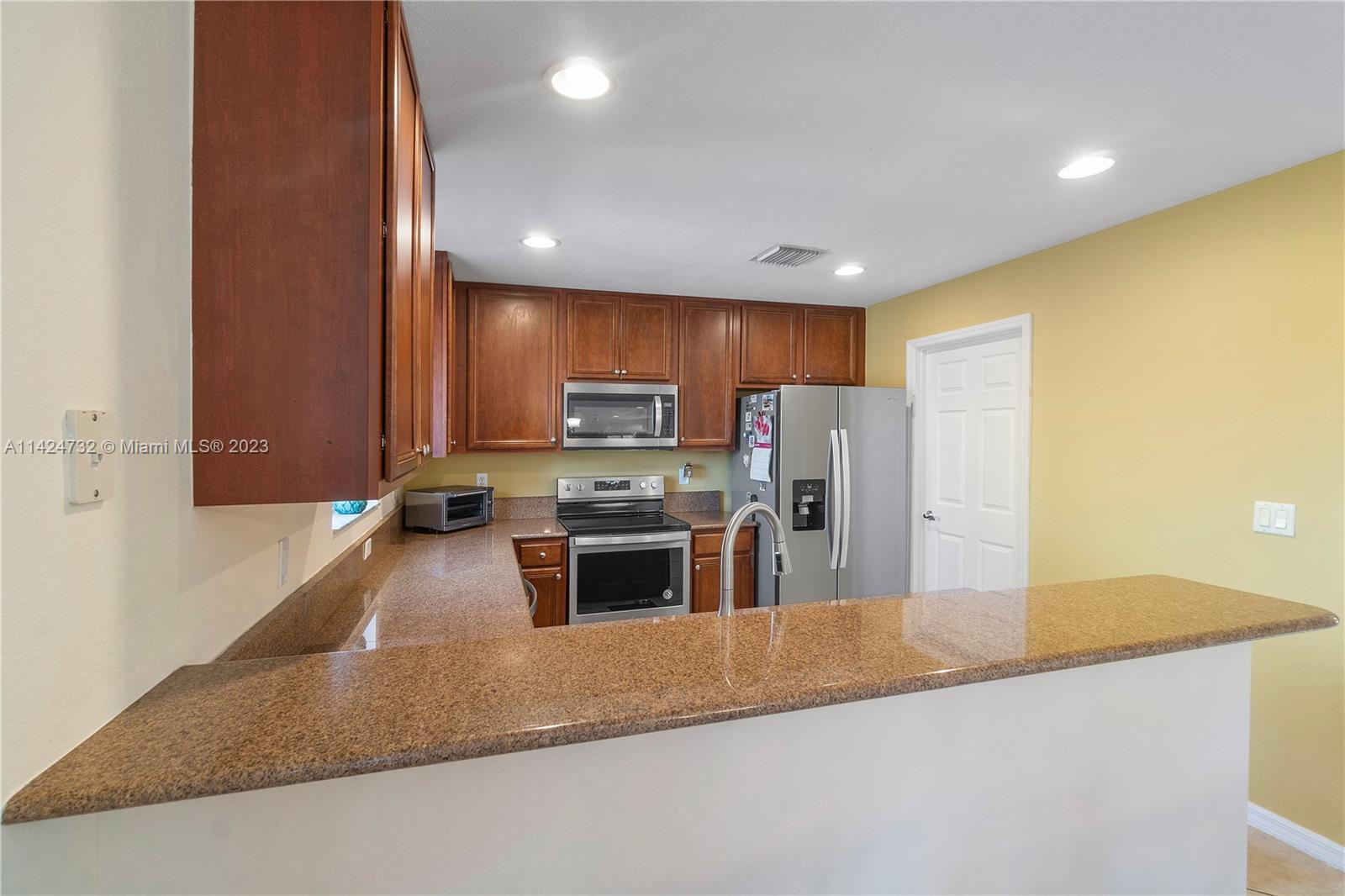Silver Falls Miramar, FL 33027 - Photo 13 of 49 a kitchen with stainless steel appliances granite countertop a sink a stove and a refrigerator with wooden floor