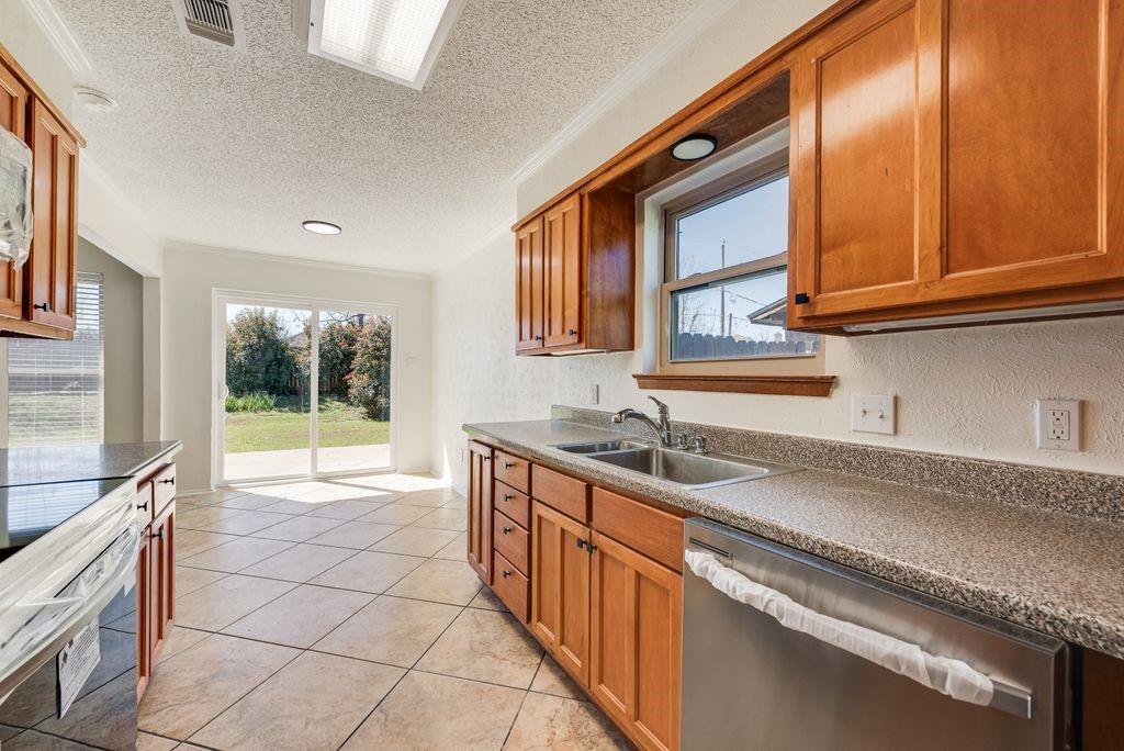 1532 Augusta Road Benbrook, TX 76126 - Photo 13 of 31 Kitchen featuring wood finish cabinets, dishwasher, electric range oven, dark countertops, and a textured ceiling