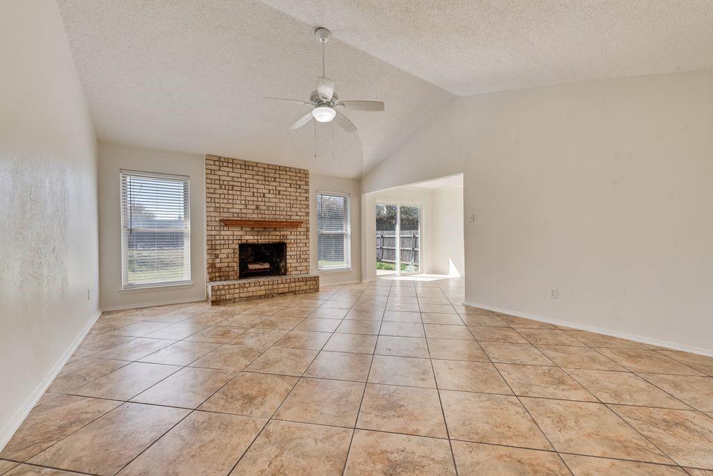 1532 Augusta Road Benbrook, TX 76126 - Photo 4 of 31 Unfurnished living room with a ceiling fan, a fireplace, and light tile patterned floors