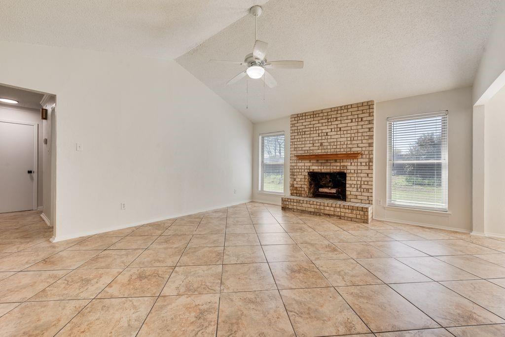 1532 Augusta Road Benbrook, TX 76126 - Photo 5 of 31 Unfurnished living room with ceiling fan, light tile patterned floors, and a fireplace