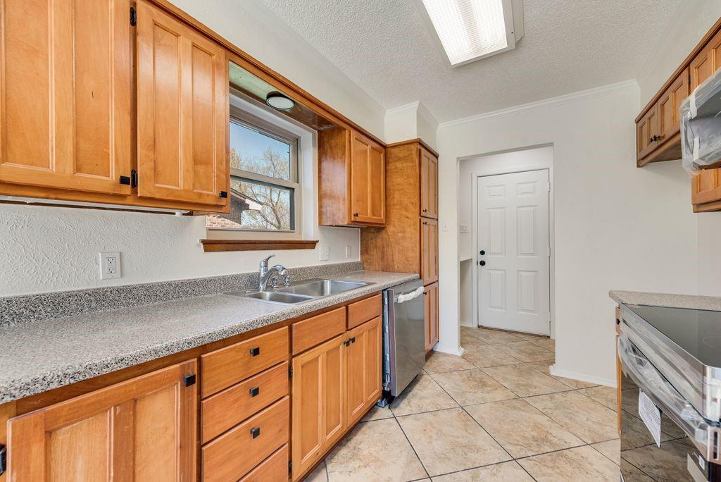 1532 Augusta Road Benbrook, TX 76126 - Photo 10 of 31 Kitchen with a textured ceiling, stainless steel appliances, light countertops, wood finish cabinets, and light tile patterned floors