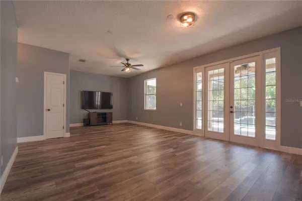 a view of an empty room with window and wooden floor
