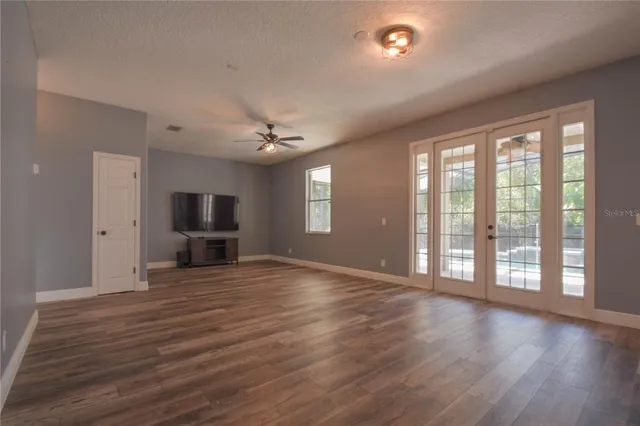 a view of an empty room with window and wooden floor