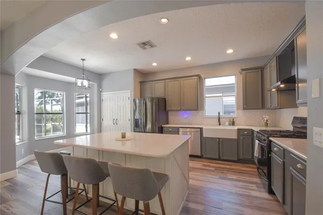 a kitchen with a dining table chairs cabinets and stainless steel appliances