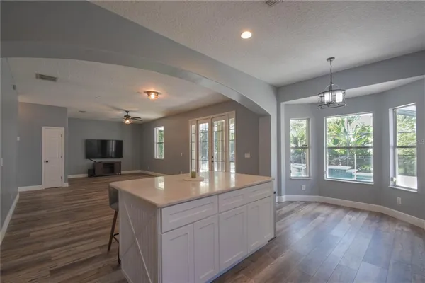 a large hall with kitchen island granite countertop a large window and a sink