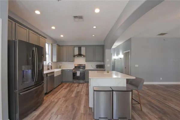 a kitchen with stainless steel appliances granite countertop a refrigerator a sink dishwasher a stove with white cabinets and wooden floor