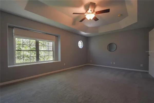 en empty room with windows and ceiling fan