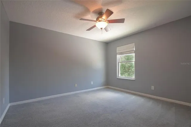 an empty room with a window and a fan