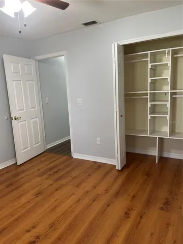a view of a room with wooden floor and a ceiling fan
