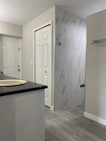 a bathroom with a granite countertop sink a mirror and a shower
