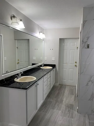 a bathroom with a granite countertop sink a toilet and shower
