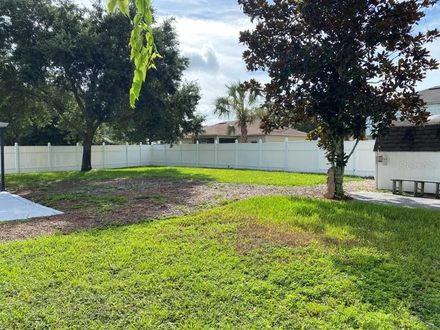 a view of a house with a yard and a large tree