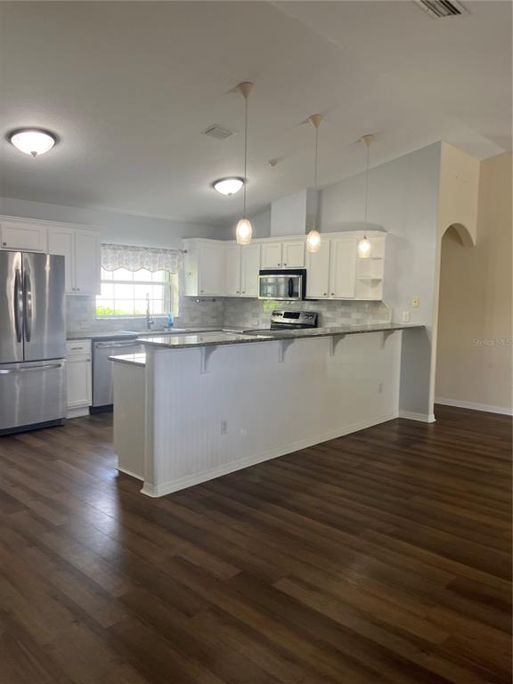 12 Prairie Lane Palm Coast, FL 32164 - Photo 7 of 41 a kitchen with stainless steel appliances granite countertop a sink a stove top oven a wooden floors and white cabinets
