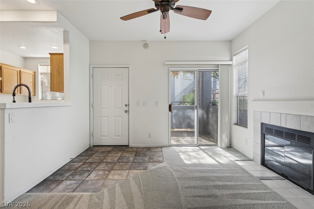 2201 Ramsgate Drive, Unit 1011 Henderson, NV 89074 - Photo 8 of 40 A living space offers a fireplace, sliding glass door, and a ceiling fan for year-round comfort.
