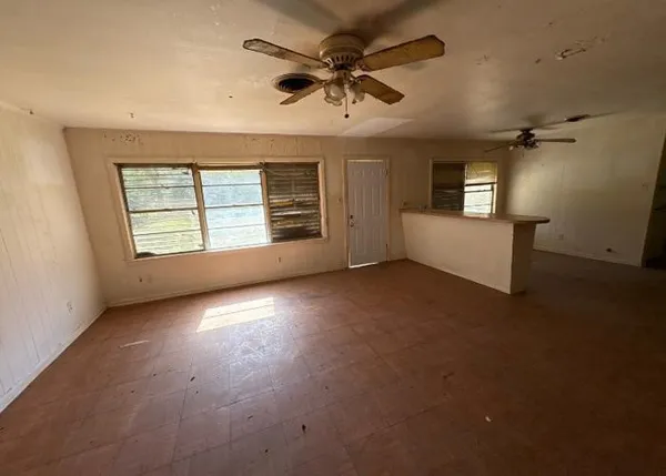 an empty room with windows and ceiling fan