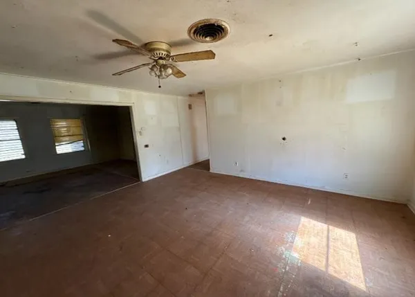 an empty room with windows and fan