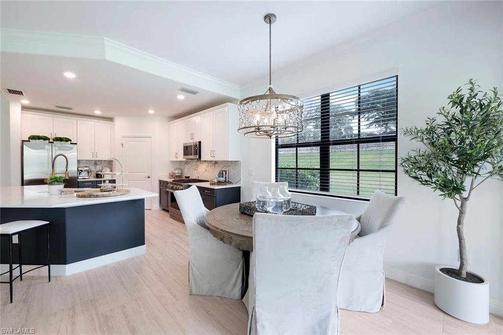 16348 Viansa Way, Unit 101 Naples, FL 34110 - Photo 10 of 34 a view of a dining room with furniture wooden floor and chandelier