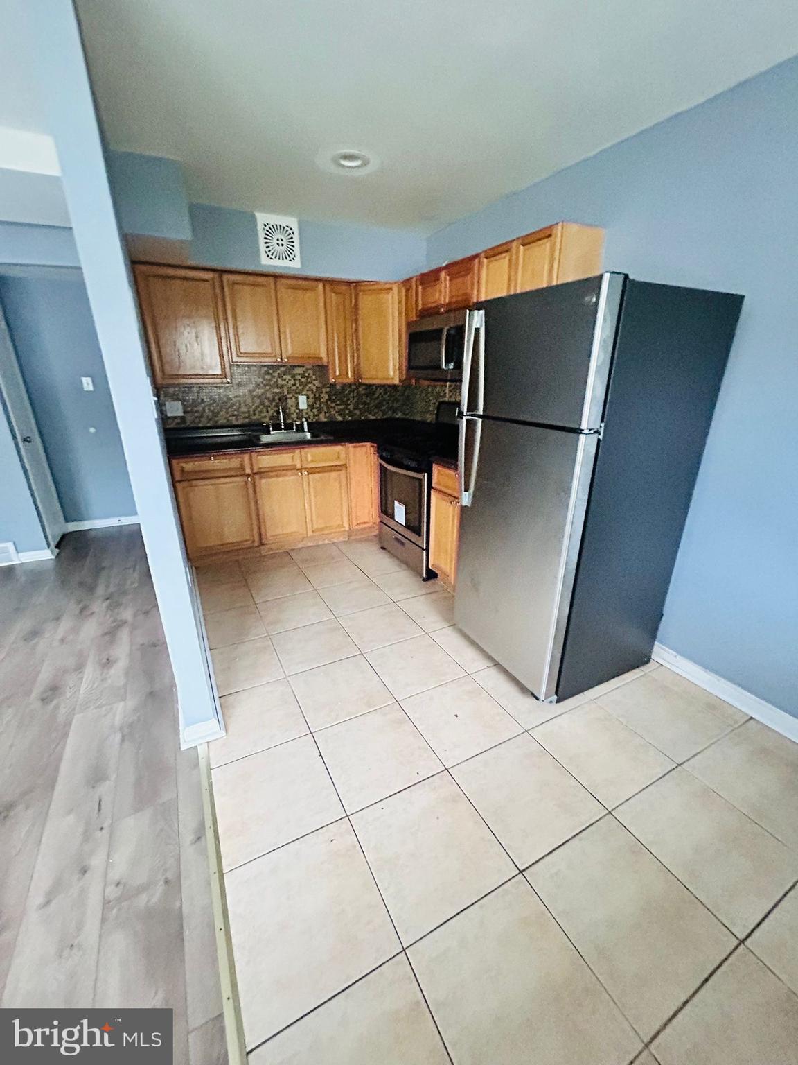 a kitchen with granite countertop a refrigerator and cabinets