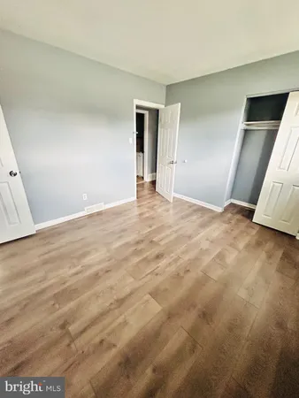 a view of an empty room with wooden floor and closet