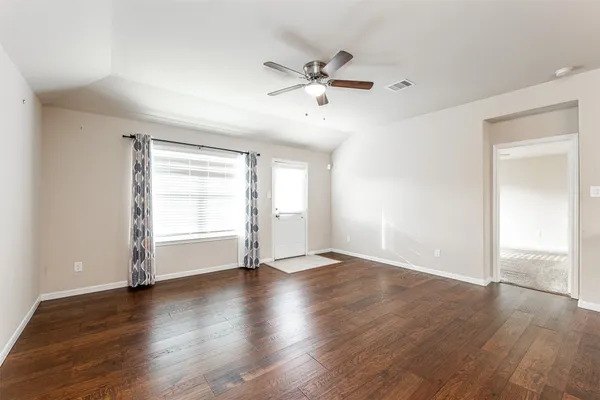 an empty room with wooden floor window and ceiling fan