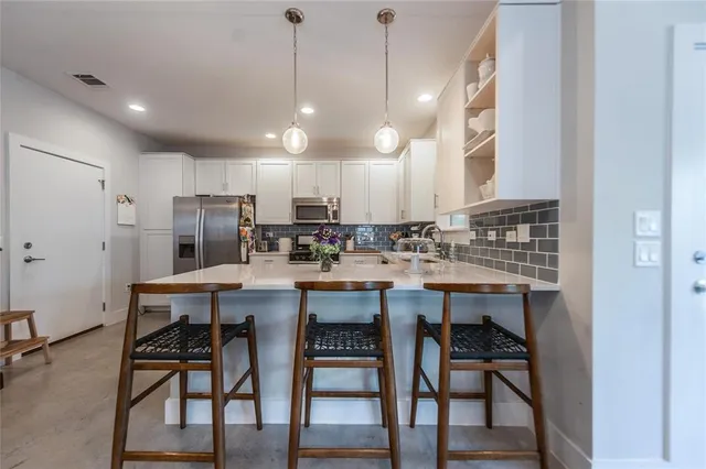 a kitchen with kitchen island a dining table chairs sink and cabinets