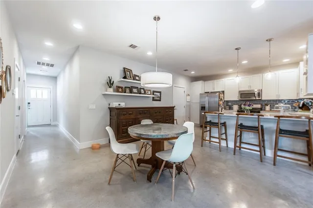 a dining room with stainless steel appliances kitchen island a table chairs and chandelier