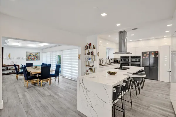 a kitchen with stainless steel appliances kitchen island granite countertop a sink and white cabinets