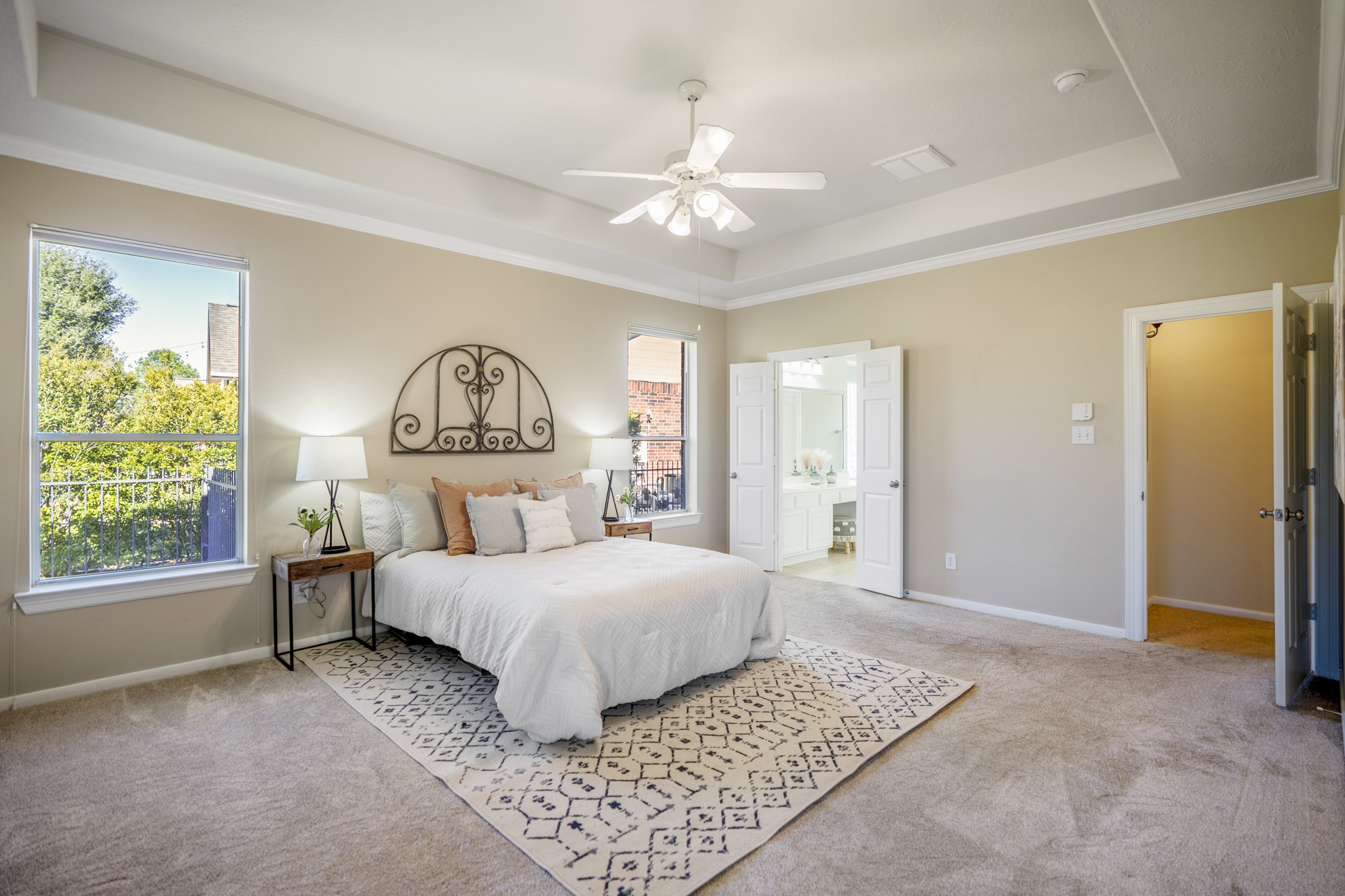 6218 Stone Trail Lane Spring, TX 77379 - Photo 17 of 50 Tucked just off the main living spaces, the primary bedroom feels airy and calm with a tray ceiling, soft natural light, and views toward the backyard. Double doors open to the en-suite bath, creating an easy flow between sleeping and getting-ready spaces while keeping the retreat feeling private and relaxed.