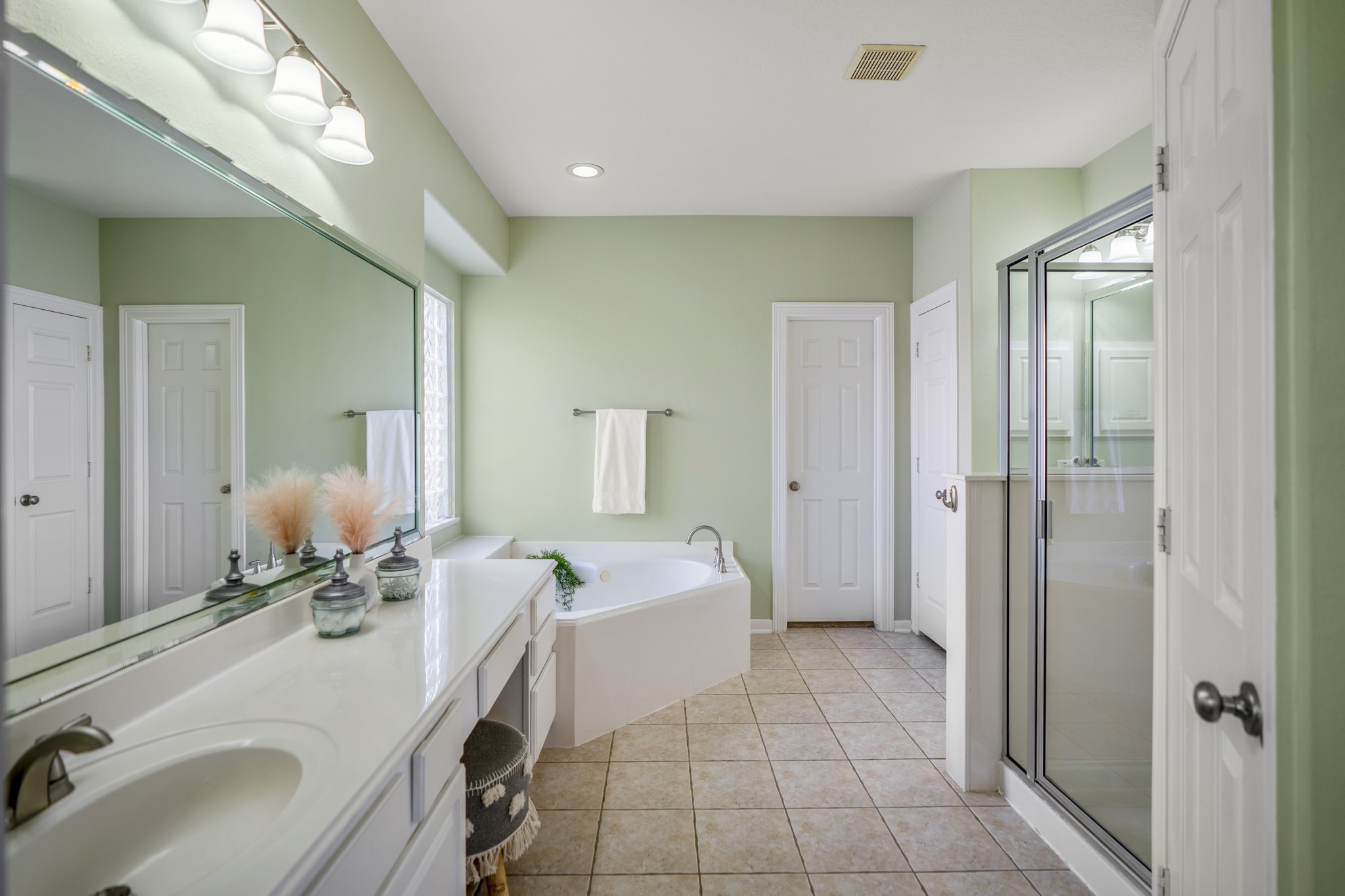 6218 Stone Trail Lane Spring, TX 77379 - Photo 18 of 50 Just beyond the bedroom, the primary bath opens up with a long vanity, soaking tub set beneath a glass block window, and a separate glass-enclosed shower. Thoughtful spacing and clean lines keep the room feeling bright and functional, with storage and layout that make daily routines feel easy and unhurried.