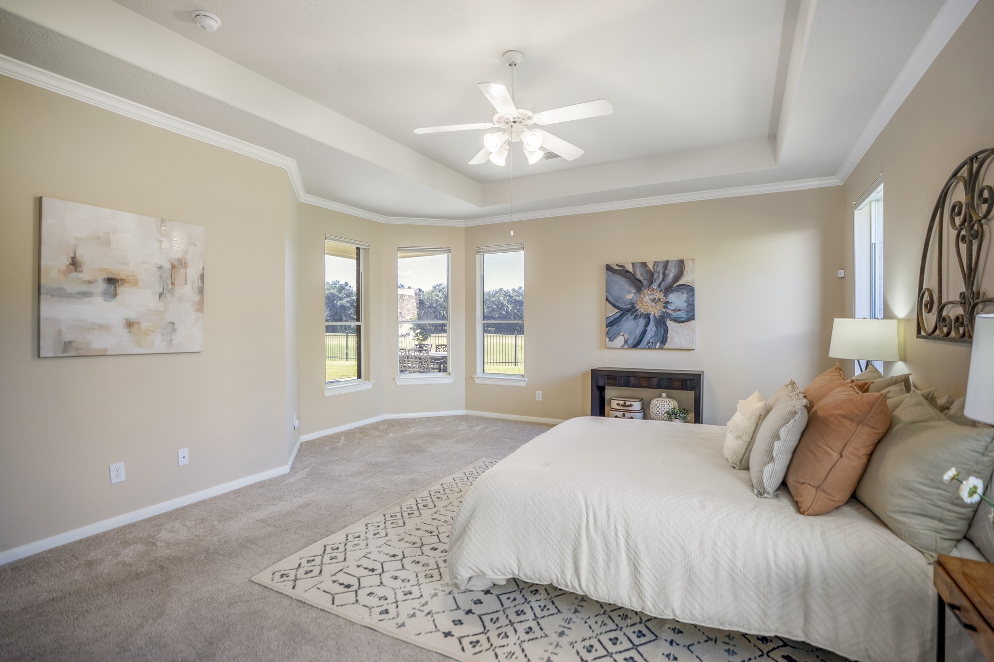 6218 Stone Trail Lane Spring, TX 77379 - Photo 21 of 50 Natural light wraps the primary bedroom through a trio of windows, highlighting the tray ceiling and soft, neutral palette. The layout leaves plenty of room for a seating nook or reading corner, while views toward the backyard add a peaceful backdrop to the space.