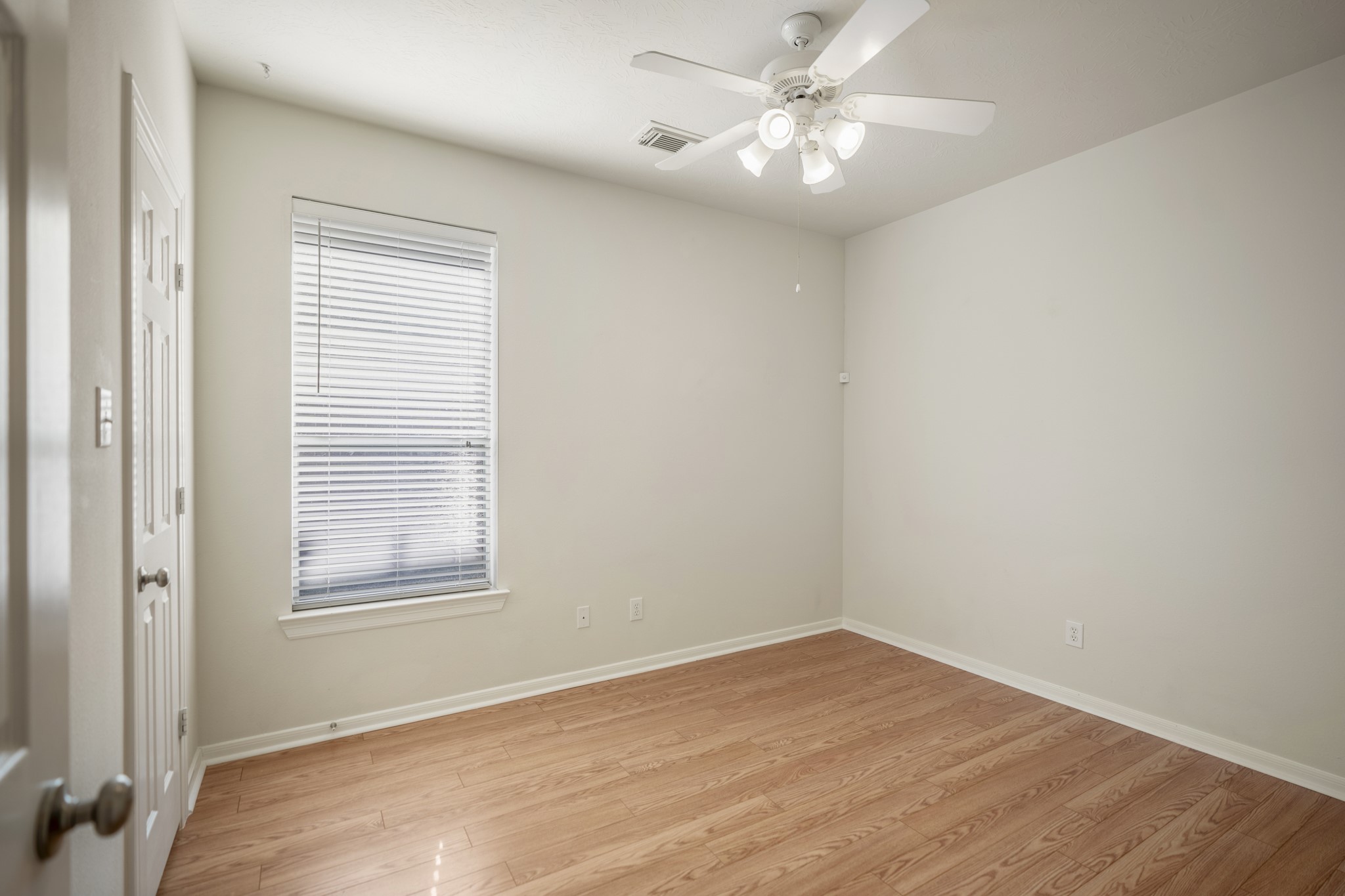 6218 Stone Trail Lane Spring, TX 77379 - Photo 23 of 50 Continuing down the hall, another secondary bedroom offers a simple, flexible layout with laminate flooring underfoot and a single window that brings in steady natural light. Positioned just off the main living areas and near the shared bath, it works well as a guest room, home office, or quiet retreat that stays connected to the rest of the home.