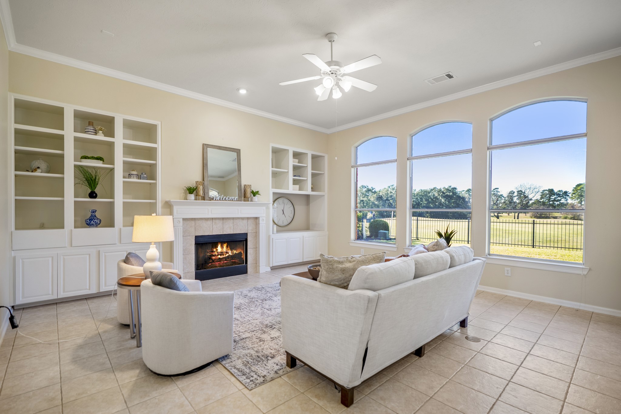 6218 Stone Trail Lane Spring, TX 77379 - Photo 7 of 50 Large windows frame the living room with open views beyond, filling the space with natural light and drawing attention to the fireplace flanked by custom built-ins. The layout invites easy conversation and everyday comfort, with room to relax, gather, and enjoy the scenery just outside.