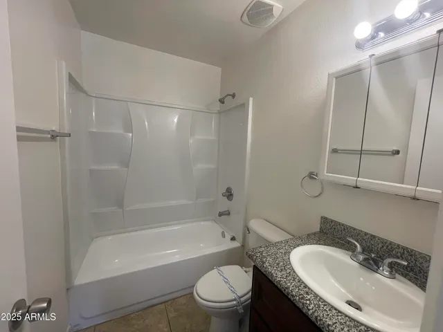a bathroom with a granite countertop sink a toilet and shower